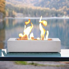 a fire pit sitting on top of a table next to a lake