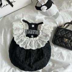 a black and white outfit with lace on the collar is sitting next to a purse