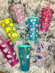 six colorful cups with straws on a furry surface