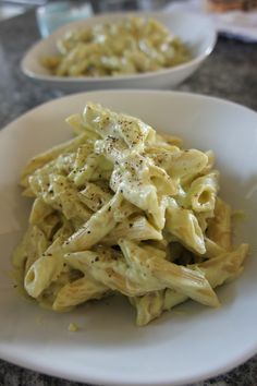 pasta with pesto and parmesan cheese in a white bowl on a table