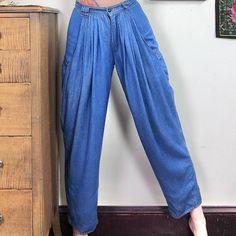 "Vintage Pleated Denim Trousers by Reserve, Styled by Biscote.  1980s High Waisted Jeans with Pleats, Baggy Thigh, and Tapered Ankle, Size Small.  These soft jeans are absolutely amazing!  Super high rise pants are made of a soft viscose that is between a chambray and a denim.  Tons of small pleats at the front of the waist help to create a baggy hip and thigh with massive fashion pockets down the sides.  The legs taper toward the ankle, and the seat of the pants is smooth and fitted.  Absolutel Baggy Vintage Denim Blue Pants, Vintage Baggy Denim Blue Pants, Vintage Baggy Denim Pants, Vintage Baggy Bottoms For Spring, Vintage Blue Baggy Bottoms, Retro Baggy Medium Wash Bottoms, Retro Baggy Denim Bottoms, 90s Relaxed Fit Tapered Leg Bottoms, 90s Style Relaxed Fit Tapered Leg Bottoms