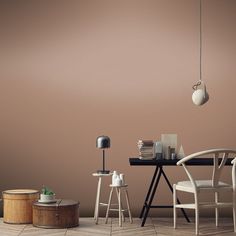 an empty room with two chairs, a table and a lamp on the floor in front of a brown wall