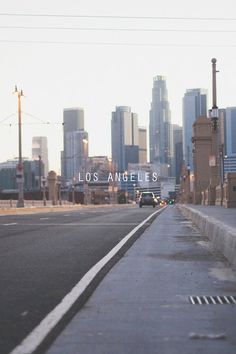 an empty street with the los angeles skyline in the background