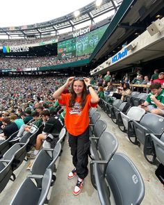 a girl in an orange shirt is at a baseball game