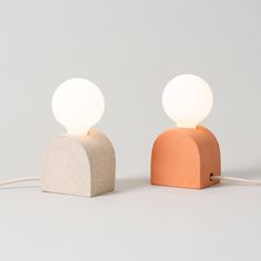 two different colored lamps sitting next to each other on a white surface with one light turned off