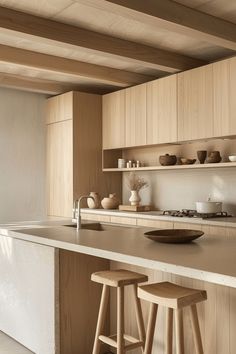 a kitchen with two stools next to an island