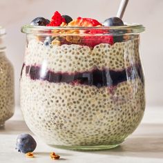 a glass jar filled with oatmeal topped with blueberries and strawberries