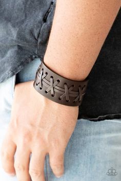 a man wearing a leather bracelet with crosses on it's wrist and holding his hand in the other direction