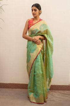 Aqua green silk chanderi saree with all over floral butti pattern, gold reverse scalloped border and stripe pattern pallu. Comes with running blouse piece.
Components: 1
Pattern: Woven
Type Of Work: Scallop and Floral Butti Pattern
Fabric: Silk Chanderi
Color: Green
Other Details: 
Contrast pink hem details
Note: The stitched blouse worn by the model is not for sale
Disclaimer: The joint fabric pieces may vary. Designers unique process ensures that the placement of fabric will always be similar Green And Pink Saree, Chanderi Saree, Scalloped Border, Handmade Textiles, Blouse For Women, Pattern Fabric, Pink Saree, Fabric Silk, Blouse Online