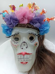 a woman's skull mask with flowers on her head and hair in the shape of a skeleton