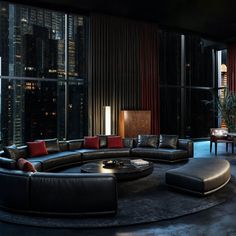 a living room filled with lots of furniture in front of a large window at night