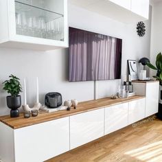 a living room filled with furniture and plants on top of a wooden floor next to a window