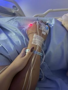 a person laying in a hospital bed with an oxygen tube attached to their arm and hand