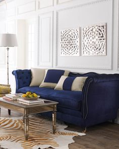 a living room with a blue couch and coffee table in front of two paintings on the wall