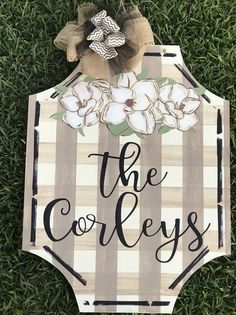 a wooden sign that says the corbleys on it with flowers and leaves