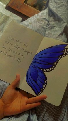 a hand holding an open book with a blue butterfly on it and the words, just when the caterpillar thought her life was over she begin to fly