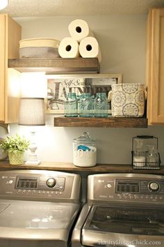 a washer and dryer sitting in a kitchen next to each other with toilet paper on the shelves above them