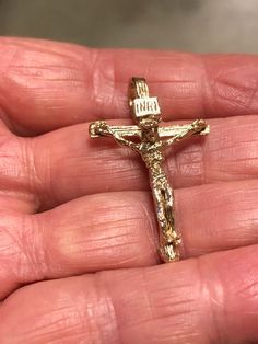 a person holding a gold cross in their left hand with the word jesus on it