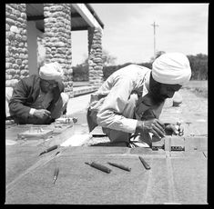 two men in turbans are working on an item with scissors and other tools