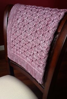 a chair with a pink knitted blanket on it