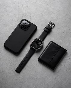 an apple watch and wallet sitting next to each other on a gray surface with a black leather case