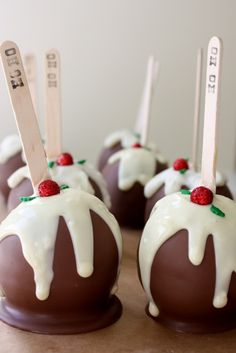 chocolate covered desserts with white icing and cherries on top are sitting on a table