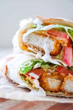 two wraps filled with meat, lettuce and tomato slices on top of each other