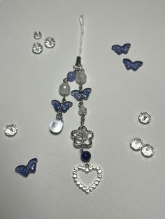 several blue and white jewelry pieces on a table with butterflies in the background, including a heart pendant