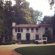 a white truck is parked in front of a large house with lots of trees around it