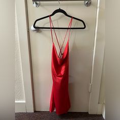 a red dress hanging on a hanger in front of a door