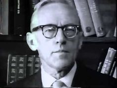 a man wearing glasses and a suit in front of books