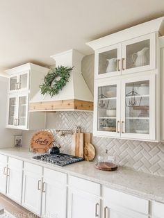 a kitchen with white cabinets and marble counter tops is pictured in this image, there is a wreath on the wall above the stove