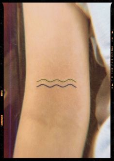 a small wave tattoo on the back of a woman's right leg, with lines drawn across it