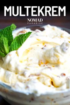 a close up of a bowl of food with whipped cream and green leaves on top