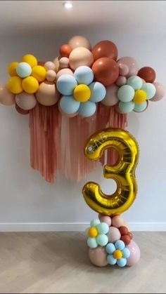 the number three balloon sculpture is decorated with balloons and streamers