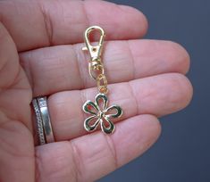 a person is holding a gold flower charm