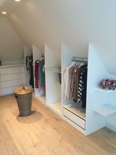 an attic bedroom with white walls and open closets on both sides, filled with clothes