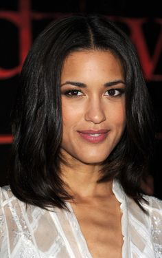 a close up of a person wearing a white shirt and posing for the camera with her hand on her hip