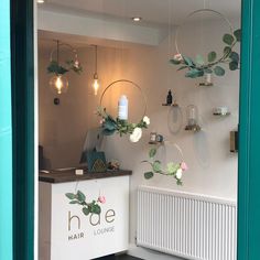 the inside of a hair lounge with flowers hanging from it's ceiling and mirrors