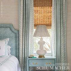 a bedroom with a bed, nightstand and window covered in bamboo blind shades on the windowsill