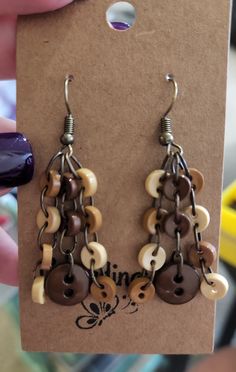 a pair of earrings with buttons hanging from it's earwires in front of a card