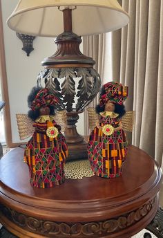 two figurines sitting on top of a wooden table next to a lampshade