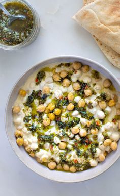 a bowl filled with food next to some pita bread