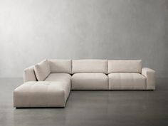 a large white couch sitting on top of a floor next to a gray wall in an empty room