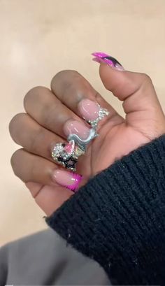 a woman with pink and silver nail polish holding her hand up to the camera,