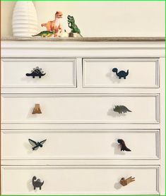 a white dresser with dinosaur knobs on it