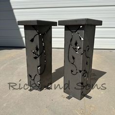 two black metal vases sitting on top of a cement floor next to a garage door