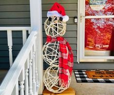 a christmas decoration on the front steps of a house with a santa hat and plaid scarf