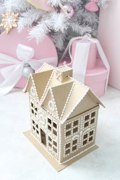 a paper house sitting on top of a table next to a christmas ornament