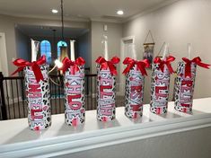 some candy wrapped in red and white paper with bows on them sitting on a mantle